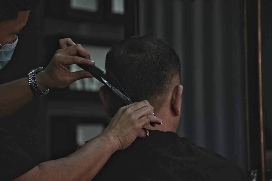 Barbeiro fazendo o acabamento de um corte na nuca